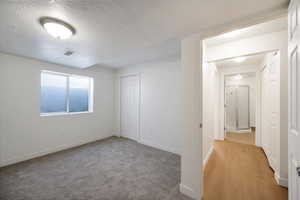 Carpeted spare room featuring a textured ceiling