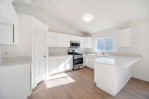 Kitchen with stainless steel appliances, sink, and white cabinets