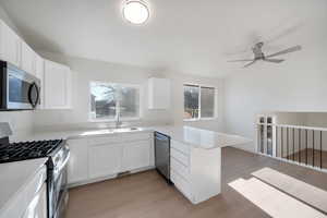 Kitchen with white cabinetry, appliances with stainless steel finishes, kitchen peninsula, and light hardwood / wood-style floors