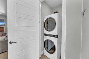 Washroom with stacked washer and dryer and light wood-type flooring