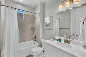 Full bathroom with vanity, shower / tub combo with curtain, and toilet