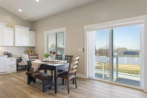 Dining space with light hardwood / wood-style flooring, built in desk, and vaulted ceiling