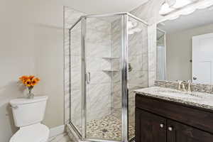 Bathroom with vanity, a shower with door, and toilet