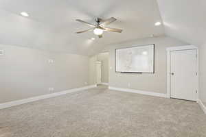 Additional living space featuring lofted ceiling, ceiling fan, light colored carpet, and a textured ceiling