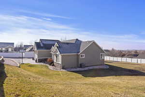 Back of property with central AC and a lawn