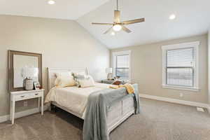 Carpeted bedroom featuring vaulted ceiling and ceiling fan