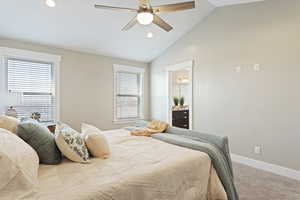 Carpeted bedroom featuring ceiling fan, lofted ceiling, and connected bathroom