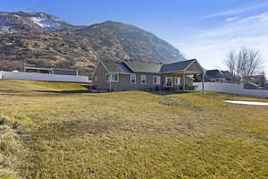 Rear view of property with a mountain view and a lawn