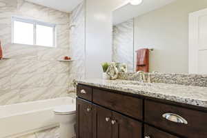 Full bathroom with tiled shower / bath combo, vanity, and toilet