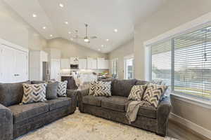 Living room with ceiling fan, high vaulted ceiling, and light wood-type flooring