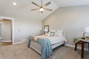 Carpeted bedroom featuring ceiling fan and high vaulted ceiling