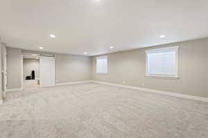 Basement featuring a barn door and light carpet