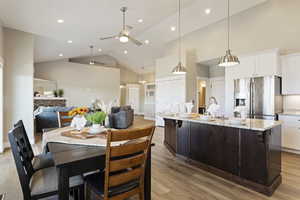 Dining area with sink, high vaulted ceiling, light hardwood / wood-style floors, and ceiling fan