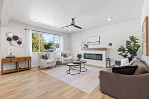 Living room featuring ceiling fan, light hardwood / wood-style floors, and a textured ceiling