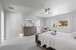 Bedroom with light carpet, a textured ceiling, and ceiling fan