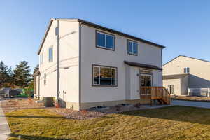 Back of house with a lawn and central air condition unit