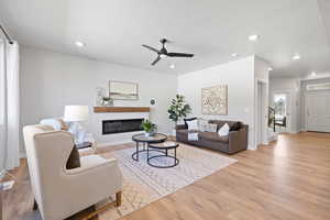 Living room featuring ceiling fan, a textured ceiling, and light wood-type flooring