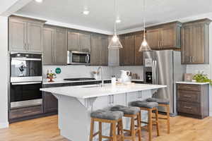 Kitchen featuring appliances with stainless steel finishes, a kitchen breakfast bar, sink, and a center island with sink