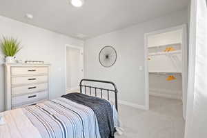 Carpeted bedroom featuring a walk in closet and a closet