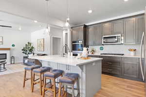 Kitchen with a kitchen bar, decorative light fixtures, an island with sink, and appliances with stainless steel finishes