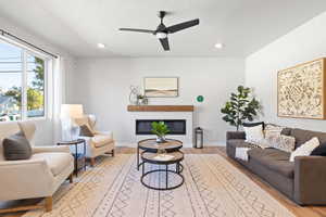 Living room with ceiling fan, light hardwood / wood-style floors, and a textured ceiling