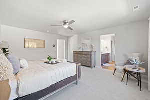 Carpeted bedroom with ceiling fan and ensuite bathroom