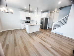 Kitchen with pendant lighting, stainless steel appliances, sink, and a center island with sink