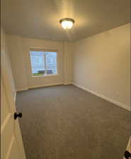 Carpeted spare room featuring a textured ceiling