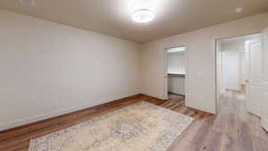 Bedroom featuring a walk in closet, light wood-type flooring, and a closet