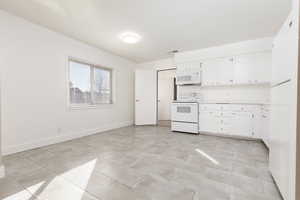 Kitchen featuring white appliances and white cabinets