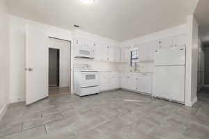 Kitchen featuring sink, white appliances, and white cabinets