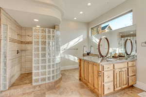 Bathroom featuring tiled shower and vanity