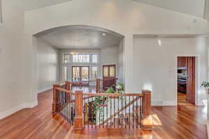 Hall featuring hardwood / wood-style flooring and a towering ceiling