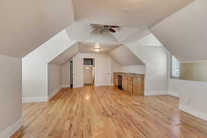 Bonus room featuring lofted ceiling, sink, ceiling fan, light hardwood / wood-style floors, and a textured ceiling