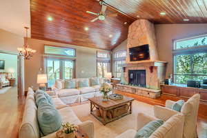 Living room featuring a fireplace, high vaulted ceiling, light hardwood / wood-style floors, and a healthy amount of sunlight