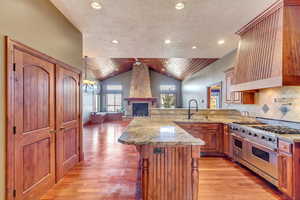 Kitchen with vaulted ceiling, a breakfast bar, tasteful backsplash, sink, and range with two ovens