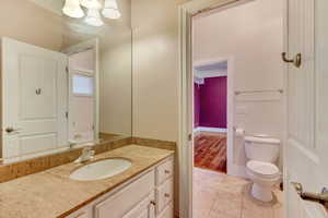 Bathroom featuring tile patterned flooring, vanity, a chandelier, and toilet