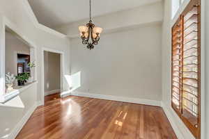 Unfurnished dining area featuring a notable chandelier and hardwood / wood-style flooring