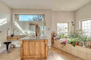 Kitchen featuring an island with sink, light stone countertops, sink, and light brown cabinetry