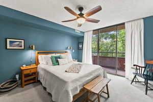 Bedroom featuring floor to ceiling windows, a textured ceiling, access to outside, carpet floors, and ceiling fan