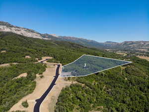 Aerial view of property and surrounding area featuring property parcel outlined and a mountain backdrop