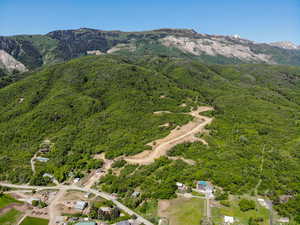 Aerial view of property and surrounding area with a mountainous background and a heavily wooded area