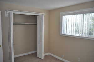 Unfurnished bedroom with light colored carpet and a closet