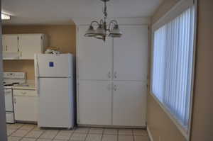 Kitchen with white cabinetry, white appliances, a chandelier, and light tile patterned floors