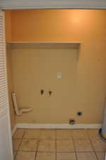 Clothes washing area with tile patterned flooring, gas dryer hookup, and hookup for an electric dryer