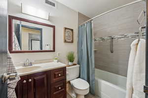 Full bathroom with toilet, vanity, and shower / bath combo