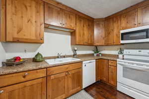 Kitchen featuring sink, white appliances, and dark hardwood / wood-style floors