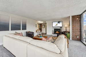 Carpeted living room featuring a fireplace, floor to ceiling natural light and walk out to two balcony areas with views