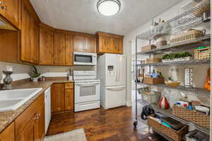 Kitchen featuring sink, white appliances, and dark hardwood / wood-style floors