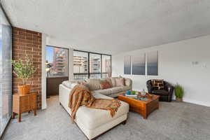 Carpeted living room featuring a fireplace, floor to ceiling natural light and walk out to two balcony areas with views